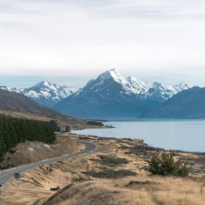 Breathtaking view of Mount Cook with a winding road, lake, and snow-capped peaks in New Zealand.