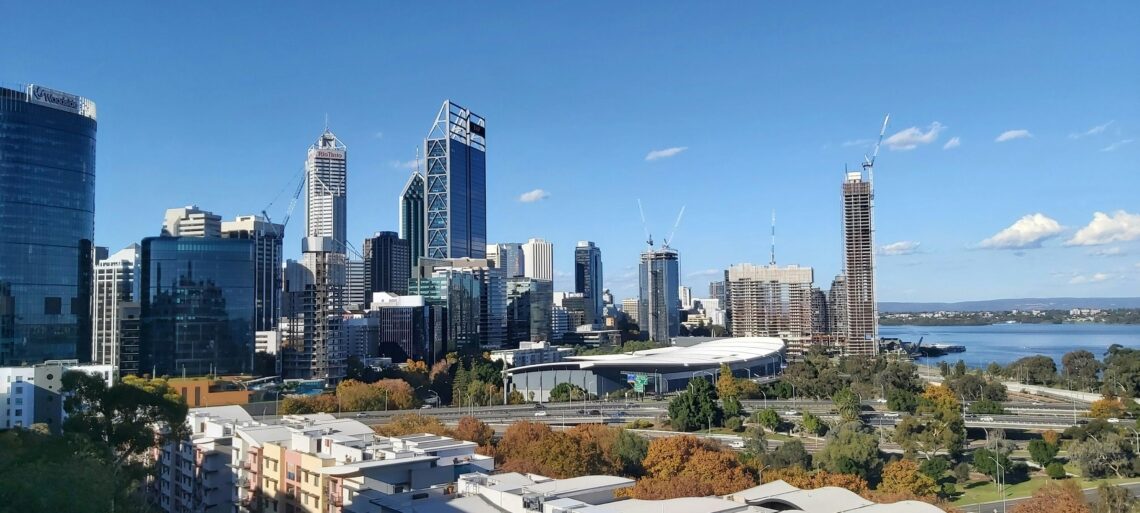 Stunning panoramic view of Perth's skyline featuring modern skyscrapers and the nearby river under a clear blue sky.