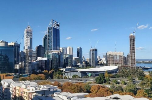 Stunning panoramic view of Perth's skyline featuring modern skyscrapers and the nearby river under a clear blue sky.