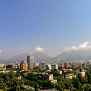 Aerial view of Tirana, Albania's capital, with mountain backdrop and clear skies.