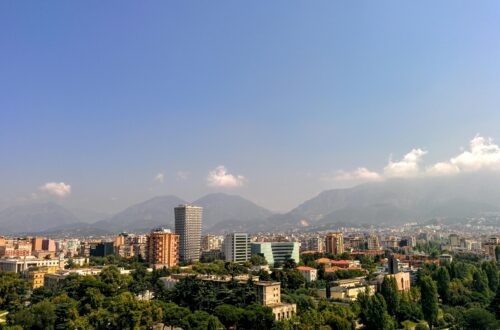 Aerial view of Tirana, Albania's capital, with mountain backdrop and clear skies.