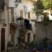 Quiet Italian street scene with laundry hanging by a charming courtyard with chairs and plants.