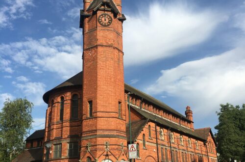 A striking red brick church and clock tower stand tall on Woodborough Road, Nottingham.