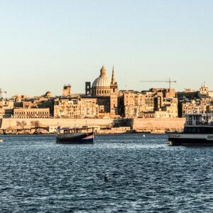 A picturesque view of Valletta's waterfront with historic architecture and boats, under clear skies.
