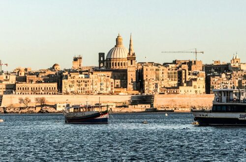 A picturesque view of Valletta's waterfront with historic architecture and boats, under clear skies.