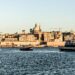 A picturesque view of Valletta's waterfront with historic architecture and boats, under clear skies.