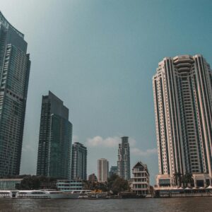 Panoramic view of Bangkok's waterfront with skyscrapers under a clear sky.