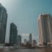 Panoramic view of Bangkok's waterfront with skyscrapers under a clear sky.