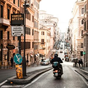 Explore a vibrant street scene in Rome with a scooter navigating the bustling urban landscape.