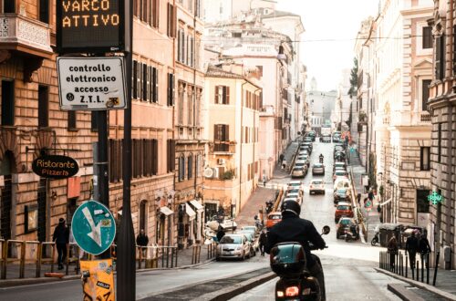 Explore a vibrant street scene in Rome with a scooter navigating the bustling urban landscape.
