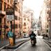 Explore a vibrant street scene in Rome with a scooter navigating the bustling urban landscape.