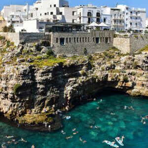 Swimmers enjoy the turquoise waters below the cliffs of Polignano a Mare in Italy.