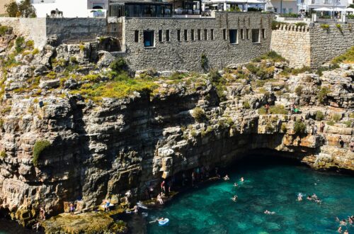 Swimmers enjoy the turquoise waters below the cliffs of Polignano a Mare in Italy.