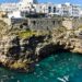 Swimmers enjoy the turquoise waters below the cliffs of Polignano a Mare in Italy.