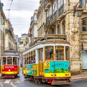 Colorful trams on a vibrant street in Lisbon, showcasing historic architecture and urban life.