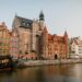 Scenic view of colorful historic buildings along the Motława River in Gdańsk, Poland.