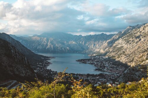 Breathtaking aerial view of the Bay of Kotor surrounded by dramatic mountains under a cloudy sky.