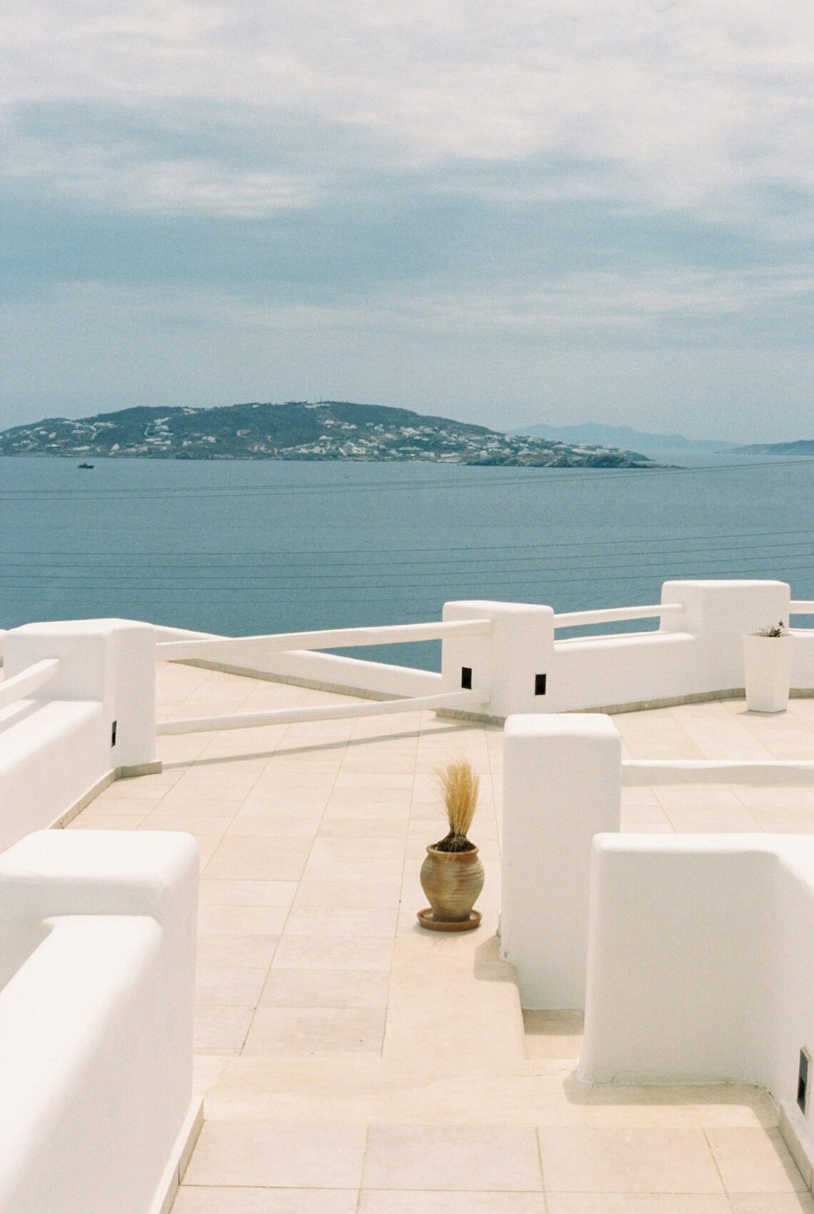 Captivating view from a Mykonos terrace with bright white architecture and Aegean Sea in the background.