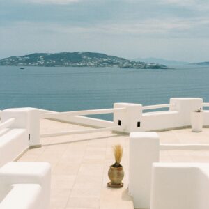 Captivating view from a Mykonos terrace with bright white architecture and Aegean Sea in the background.