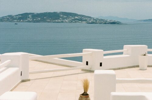 Captivating view from a Mykonos terrace with bright white architecture and Aegean Sea in the background.