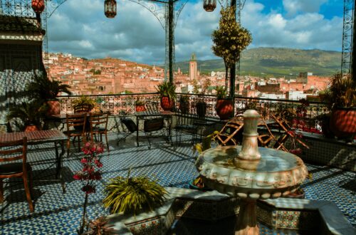 Enjoy a stunning view from a traditional Moroccan terrace overlooking Marrakesh under a vibrant sky.