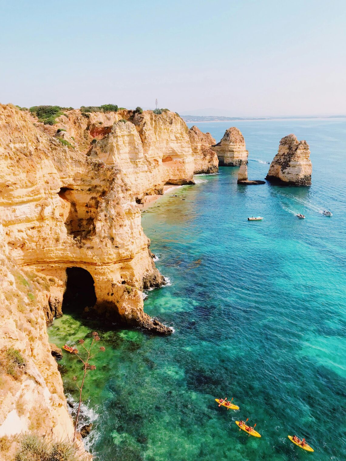 Stunning view of Algarve's cliffs and kayakers exploring clear turquoise waters in Lagos, Portugal. Perfect seascape.