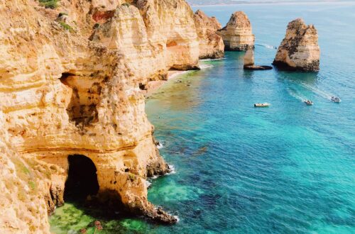 Stunning view of Algarve's cliffs and kayakers exploring clear turquoise waters in Lagos, Portugal. Perfect seascape.