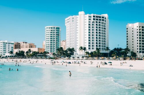 Scenic view of modern hotels along the beachfront in Cancun, Mexico, with clear blue waters.
