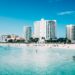 Scenic view of modern hotels along the beachfront in Cancun, Mexico, with clear blue waters.