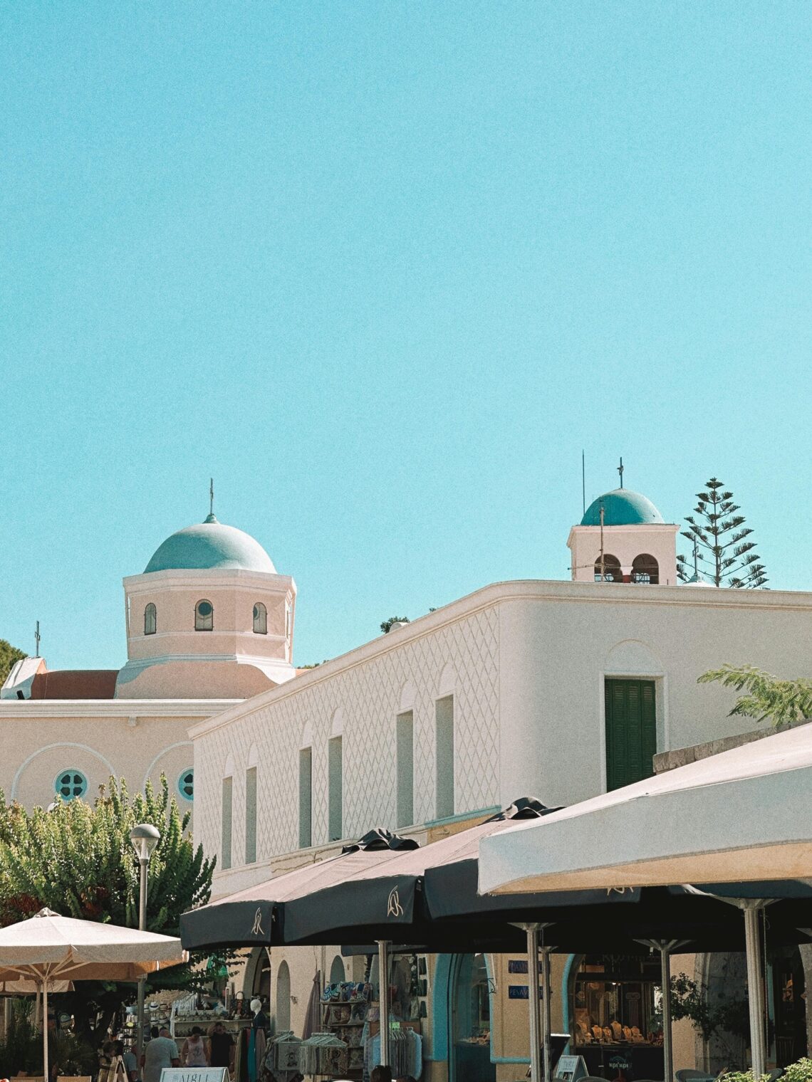 Discover the tranquil beauty of Kos, Greece, featuring iconic blue domes and white buildings under a bright summer sky.