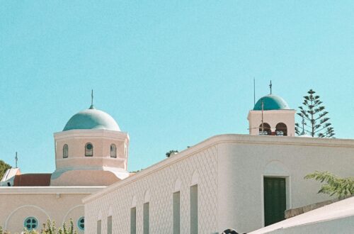Discover the tranquil beauty of Kos, Greece, featuring iconic blue domes and white buildings under a bright summer sky.